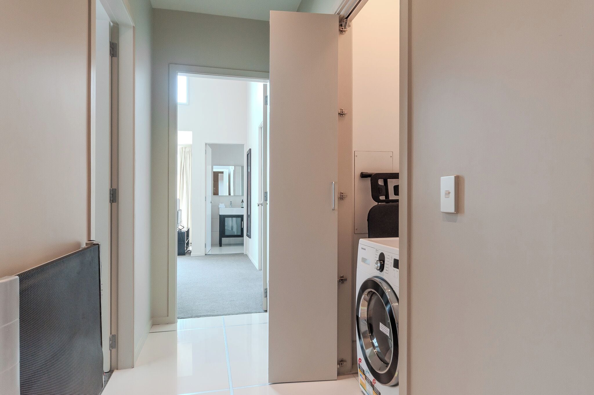 Un área de lavandería con lavadora y secadora, un radiador y una puerta que da a la cocina.