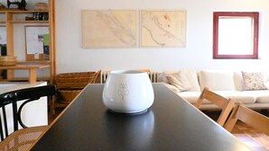 Zona pranzo con tavolo, sedie, un vaso bianco e due opere d'arte appese al muro.