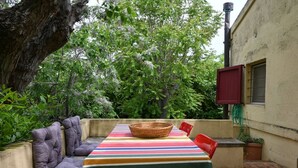 Un patio con tovaglia a righe, un cesto di vimini e sedute imbottite.