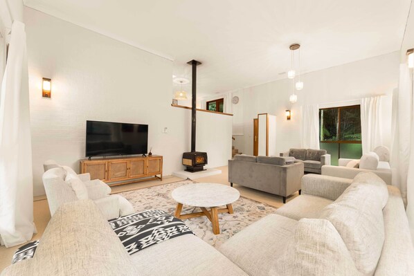 A modern living room with a flat-screen TV, a fireplace, and a sofa set.