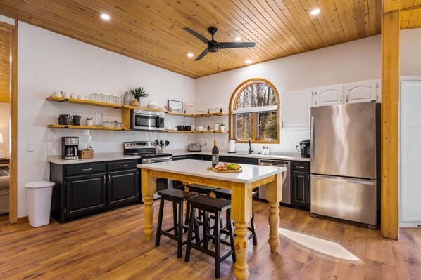 A modern kitchen with wooden cabinets, a central island, and a stainless steel refrigerator.