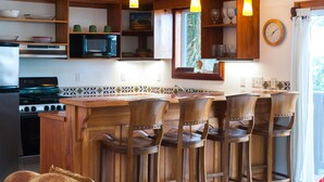 Cozinha com armários de madeira, micro-ondas, fogão e banquetas de bar.