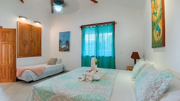 A hotel room with a bed, a bench, a painting, and a window with curtains.