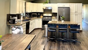 Eine moderne Küche mit weißen Schränken, Edelstahlgeräten und einem Essbereich aus Holz.