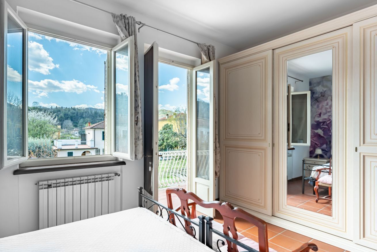 Une chambre avec une grande fenêtre, un radiateur, un lit et une vue sur un balcon.