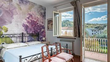 Una camera da letto con un letto, una panca, una finestra vista e un affresco al muro.