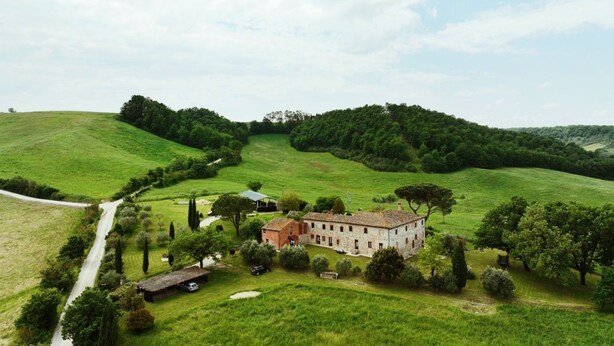A rural property with a stone building surrounded by lush green fields and trees.