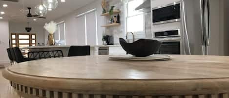 Una cocina moderna con una mesa redonda de comedor, electrodomésticos de acero inoxidable e iluminación colgante.