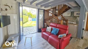 A modern living room with a red leather sofa, a small wooden table, and a staircase leading to an upper level.