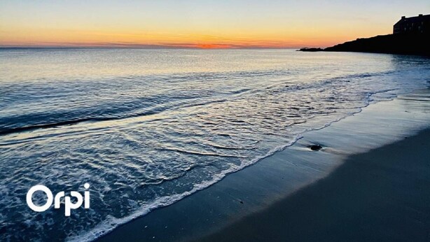 A beach with calm waters and a clear sky.