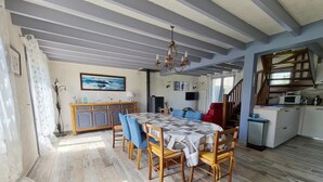 A spacious dining area with a large table and chairs, a chandelier, and a kitchen area with a microwave and cabinets.