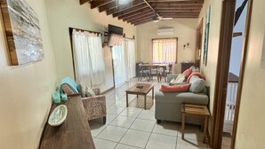 A spacious living room with a high ceiling, tiled floor, and a dining area with a table and chairs.