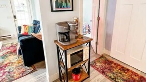 A cozy living room with a wooden ceiling, a coffee machine on a wooden table, a colorful rug, and a framed picture on the wall. - Love Shack Private Hot tub  steps to Jet/Town (Port Clinton)