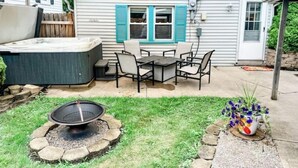 A backyard with a hot tub, patio furniture, a fire pit, and a shaded area. - Love Shack Private Hot tub  steps to Jet/Town (Port Clinton)