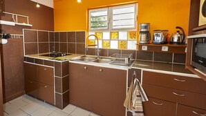 Una cocina compacta con gabinetes marrones, un lavamanos de acero inoxidable y un ventanal con vidrio esmerilado.
