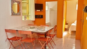 Un comedor con una mesa, sillas, televisor y un espejo en la pared.