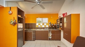 Cocina compacta con una isla central, ventilador de techo y una ventana.
