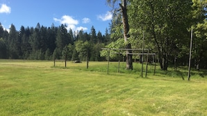 An open grassy field with a metal structure, trees, and a clear sky. - Wildlife, Nature, Glamp 1 (Cave Junction)