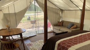 A tented accommodation with a bed, a sofa, a table, and a chair. - Wildlife, Nature, Glamp 1 (Cave Junction)