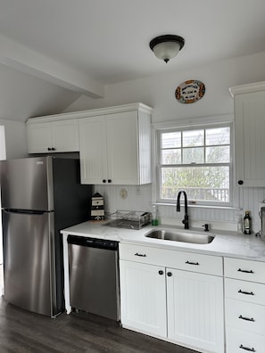 A kitchen with white cabinetry, stainless steel appliances, a window, and a decorative plate on the wall.