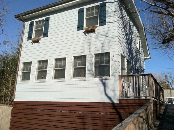 A two-story building with a brown lower section and white upper section, featuring multiple windows and a small porch area. - Large Beach House Steps From Town and Ocean (Ocean Beach)