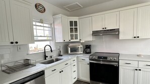 Une cuisine moderne avec des meubles blancs, des appareils en acier inoxydable et un plancher en bois.