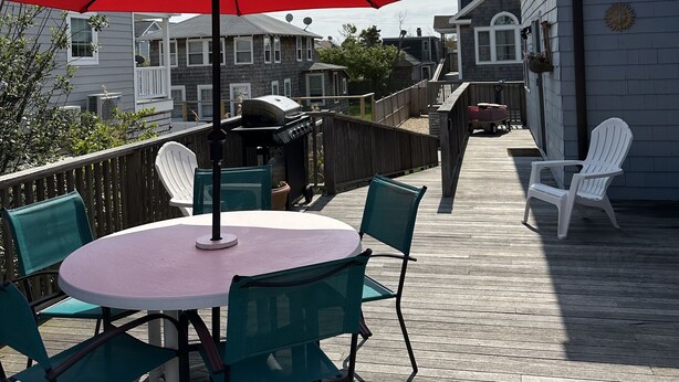 Une terrasse avec une table ronde, des chaises et un parasol rouge.
