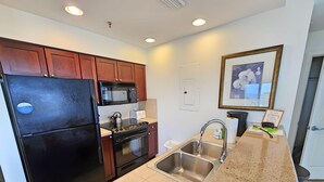 Una cocina moderna con refrigerador negro, pileta de acero inoxidable y encimera de granito.