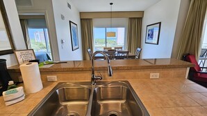 Una cocina moderna con un lavamanos doble, encimera de granito y un comedor con mesa y sillas.