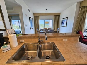 A modern kitchen with a double sink, granite countertop, and a dining area with a table and chairs.