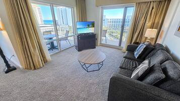 A hotel room with a balcony, a TV, a sofa, and a small table.