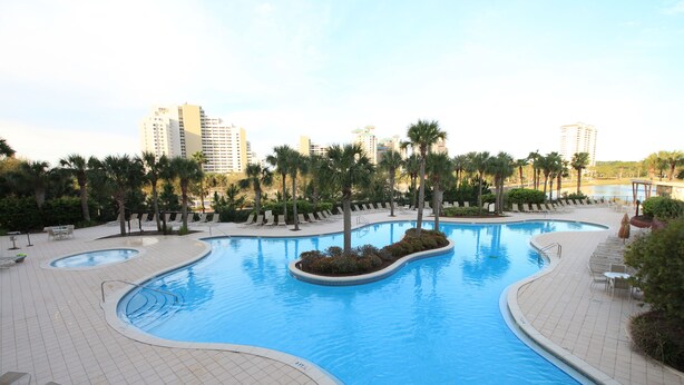 A swimming pool with a curved design, surrounded by palm trees and lounge chairs. - Luau 6533 South Facing Gulf Views! |Wifi | Tram Included (Miramar Beach)