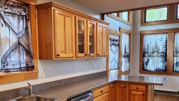 Una cocina con armarios de madera, pileta de acero inoxidable y lavavajillas.