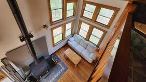 Un espacio tipo loft con chimenea, un sofá y ventanas amplias.