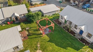 A residential area with a wooden swing set, a fire pit, and a well-maintained lawn. - Salmon River Cabin #210 (Riggins)