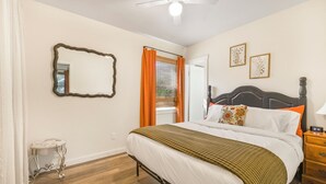 A bedroom with a bed, a nightstand, a mirror, and a ceiling fan. - Salmon River Cabin #210 (Riggins)