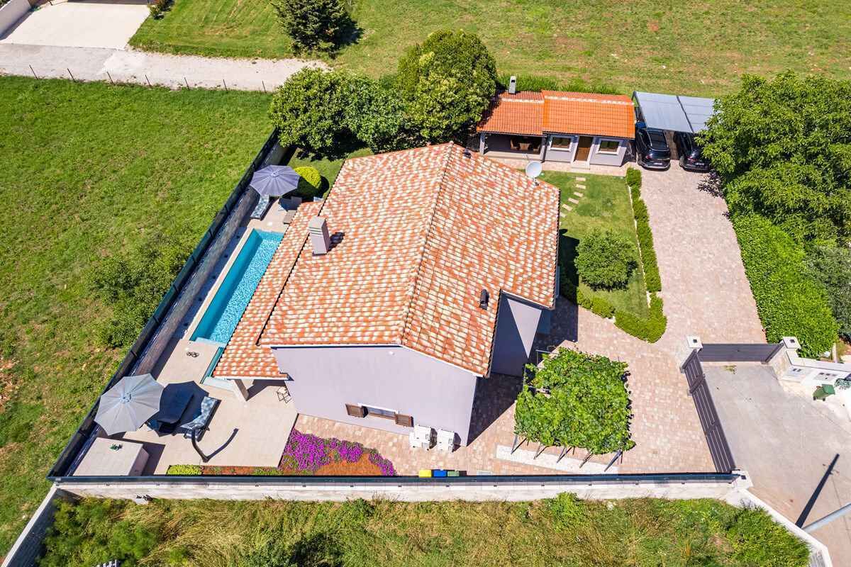 Vue aérienne d’une propriété résidentielle dotée d’une piscine, d’un patio couvert et d’un garage séparé.