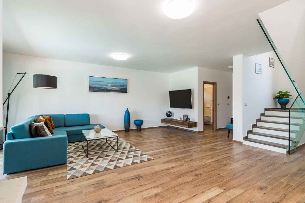 Un saló modern amb un sofà blau, una taula de centre i una catifes amb disseny.
