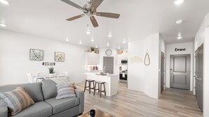 Un salon moderne avec un canapé gris, une table basse en bois et un ventilateur de plafond.