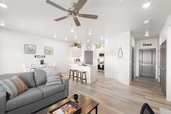 A modern living room with a gray sofa, wooden coffee table, and a ceiling fan.