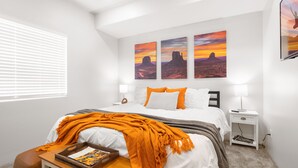Une chambre à coucher avec un lit, une table de chevet, une lampe et une fenêtre avec des stores.