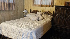 A bedroom with a large bed, wooden panel walls, a wooden cabinet, and a patterned bedspread. - Bear Lair 1 Pet friendly,walking trails,hot tub (Albrightsville)