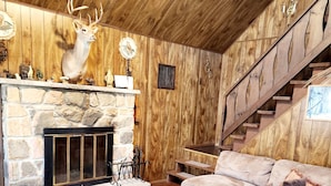 A cozy living room with a stone fireplace, a mounted deer head, a staircase, and a large sectional sofa. - Bear Lair 1 Pet friendly,walking trails,hot tub (Albrightsville)