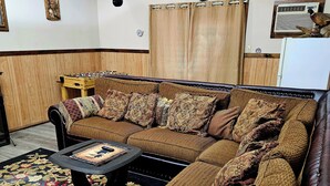 A cozy living room with a brown sofa, patterned cushions, a coffee table, and a wooden side table. - Bear Lair 1 Pet friendly,walking trails,hot tub (Albrightsville)