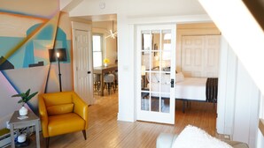 Una sala de estar moderna con un sillón amarillo, un sofá blanco y un comedor al fondo.
