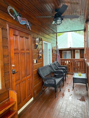 Step outside to a charming porch with a large door, wicker chairs, and a small table.