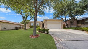 A residential area with a well-maintained lawn, a driveway, and houses with brick exteriors.