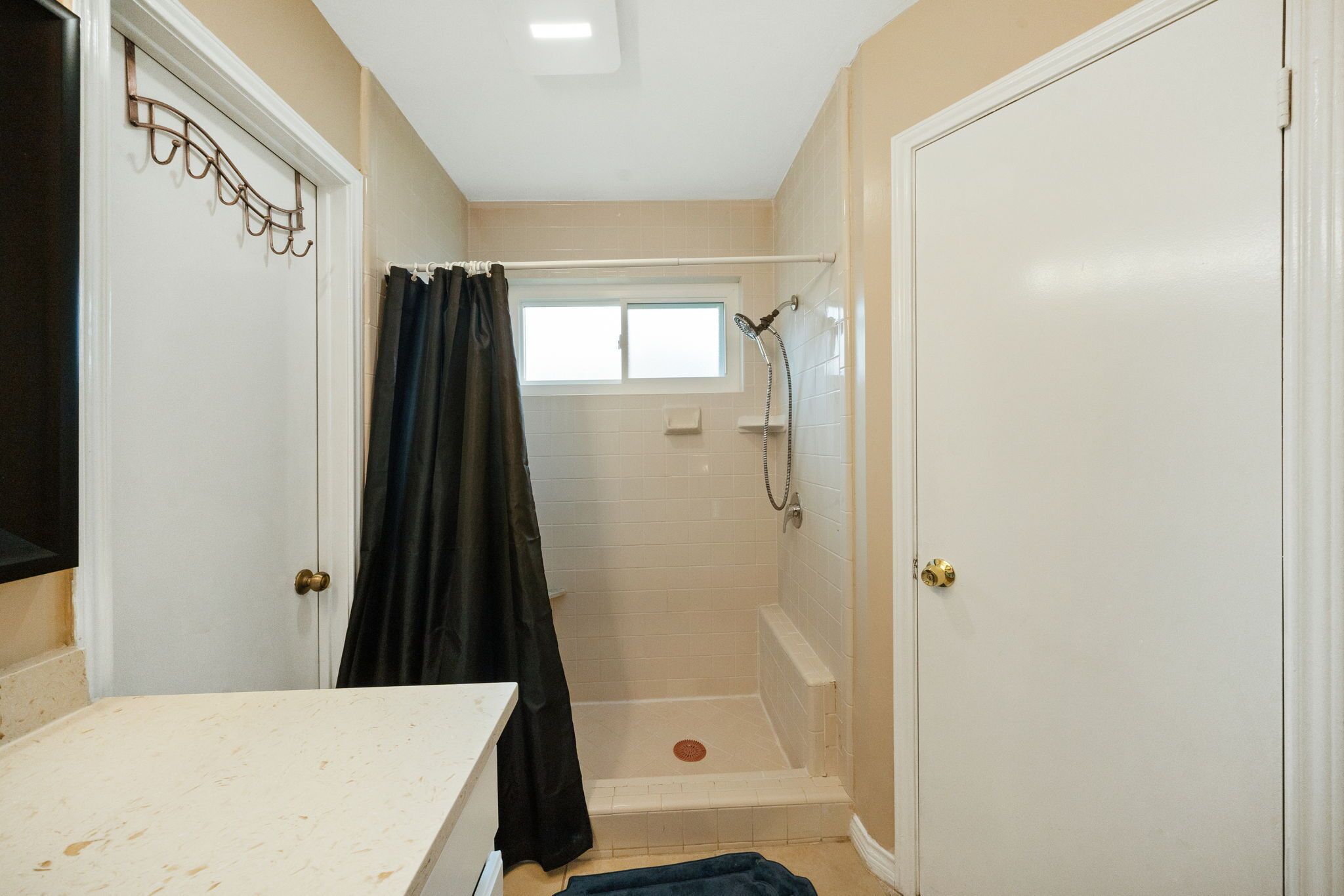 A bathroom with a shower, a window, and a door.