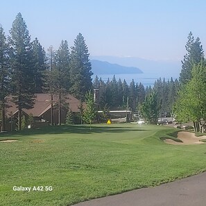 A golf course with a clear view of the water and mountains in the background.