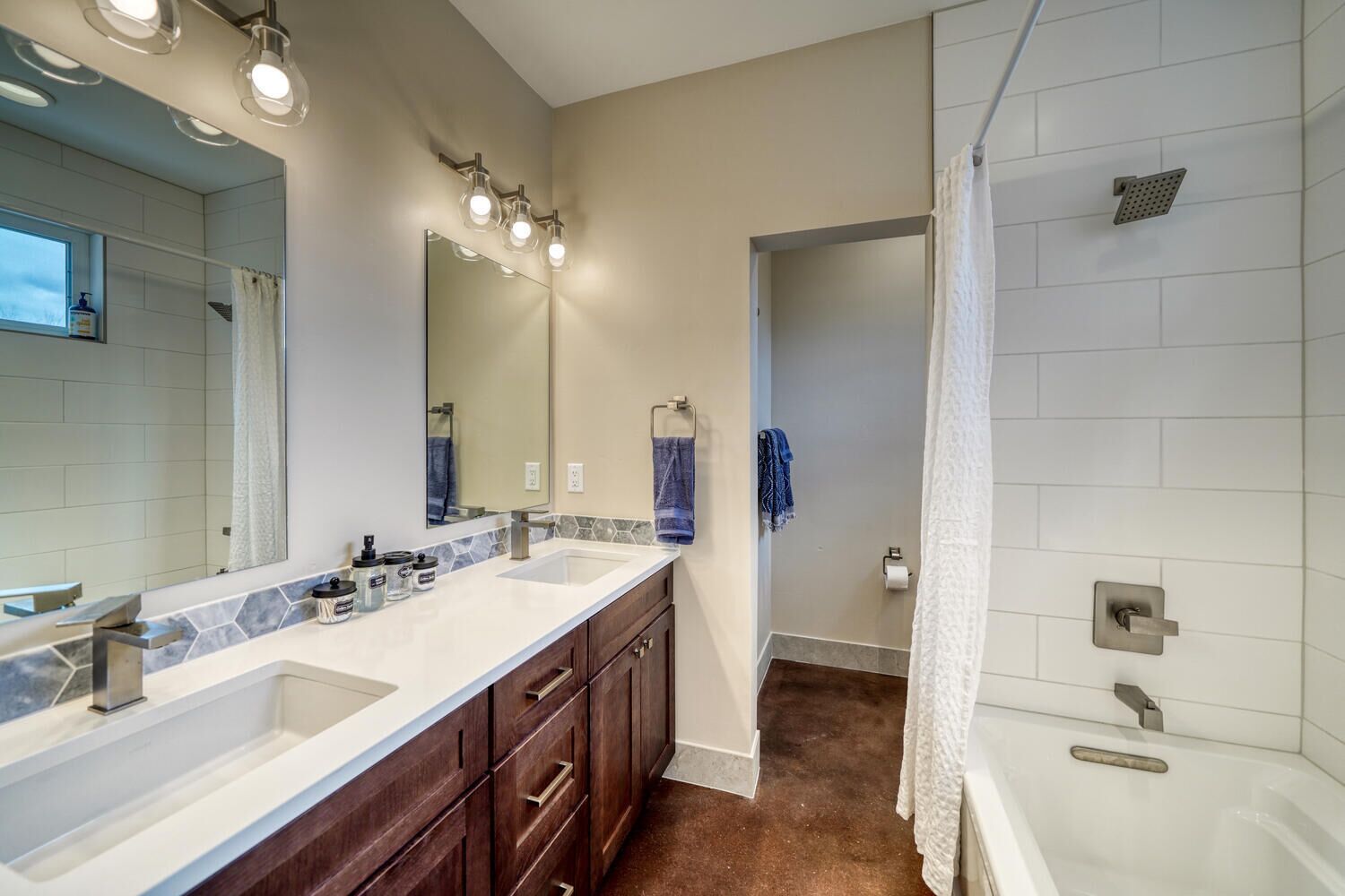 Une salle de bain moderne avec un meuble-lavabo à deux vasques, un grand miroir et un espace douche.